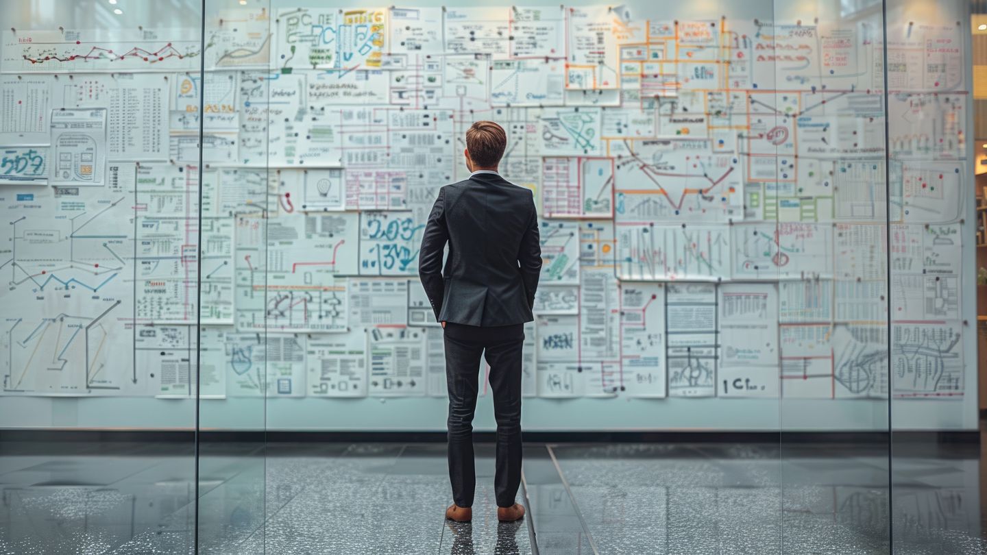businessman standing in front of planning wall with charts and graphs